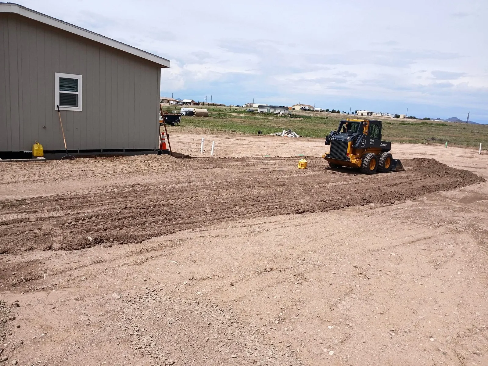 Skid steer finish grading beside a home